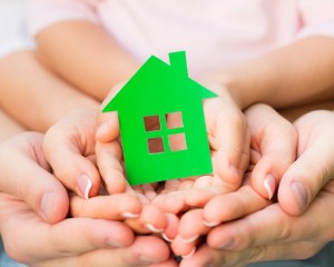 Family holding green paper house